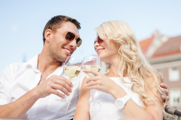 férias de verão e conceito de namoro - casal sorridente com óculos de sol bebendo vinho no café