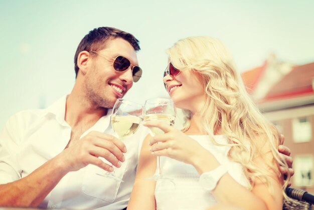 férias de verão e conceito de namoro - casal sorridente em óculos de sol bebendo vinho no café