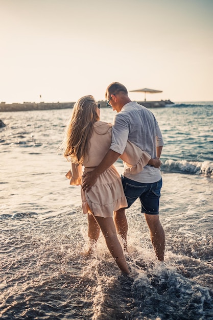Férias de verão e viagens Mulher e homem sexy na água do mar ao pôr do sol Casal apaixonado relaxa na praia do nascer do sol Relacionamento amoroso de um casal curtindo um dia de verão juntos