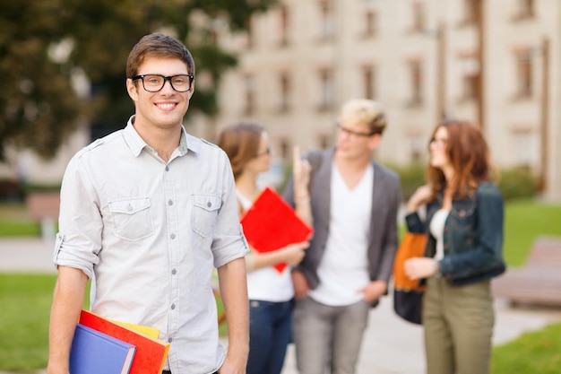 Férias de verão, educação, campus e conceito adolescente - adolescente sorridente em óculos com colegas nas costas