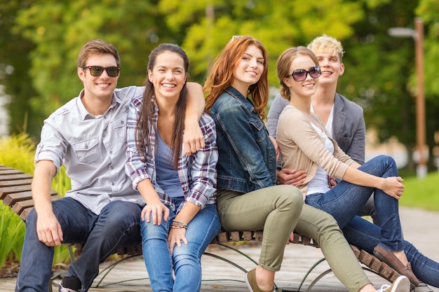 férias de verão, educação, campus e conceito adolescente - grupo de estudantes ou adolescentes saindo ao ar livre