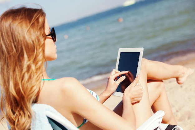 Férias de verão, férias, tecnologia e internet - garota olhando para o tablet pc na cadeira de praia