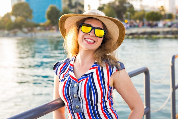 Férias de verão, férias, viagens e conceito de pessoas - sorrindo rindo jovem usando óculos escuros e chapéu na praia sobre o mar.