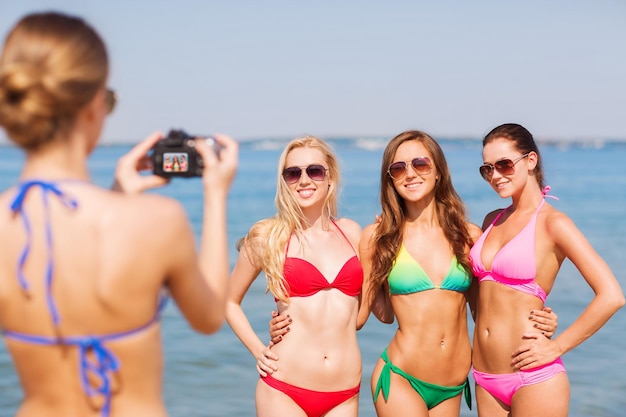 férias de verão, gesto, viagens e conceito de pessoas - grupo de mulheres jovens sorridentes fotografando pela câmera e acenando com as mãos na praia