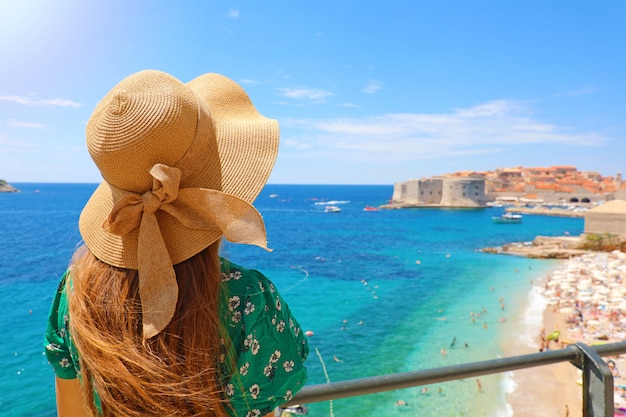 Férias de verão na Croácia. Vista traseira de jovem com chapéu de palha e vestido verde com a cidade velha de Dubrovnik no fundo, Croácia, Europa.