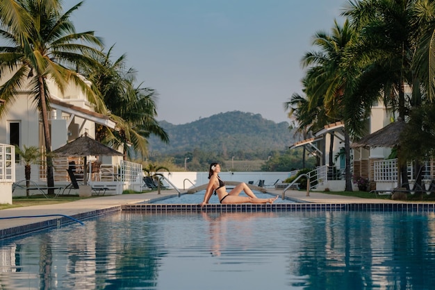 Férias de verão na mulher do hotel de luxo relaxando perto da bela piscina Beleza e cuidados com o corpo Vista traseira sem rosto