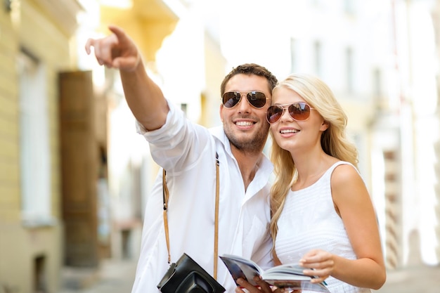 Férias de verão, namoro, férias na cidade e conceito de turismo - casal com câmera e guia de viajantes