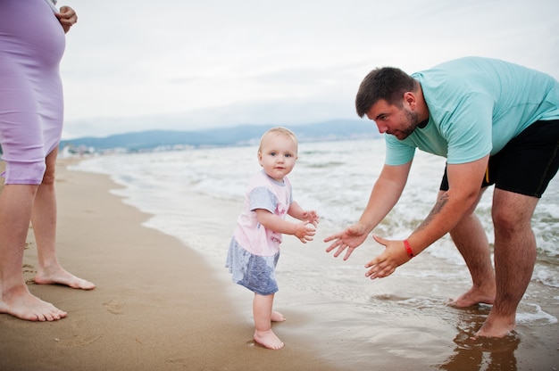 Férias de verão. Pais e pessoas atividade ao ar livre com crianças. Boas férias em família. Pai, mãe grávida, filha bebê na praia de areia do mar.