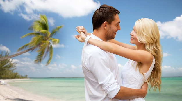férias de verão, pessoas, amor, viagens e conceito de namoro - casal feliz abraçando sobre fundo de praia tropical