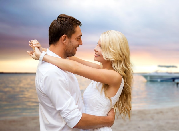 férias de verão, pessoas, amor, viagens e conceito de namoro - casal feliz abraçando sobre o fundo da praia do pôr do sol