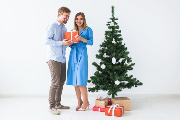 Férias e conceito de celebração - homem dando um presente de Natal para a namorada.