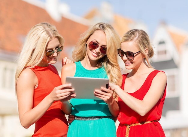 férias e conceito de turismo - lindas garotas loiras olhando para um tablet pc na cidade