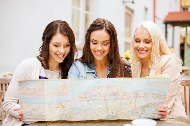férias e conceito de turismo - lindas garotas olhando para o mapa turístico da cidade
