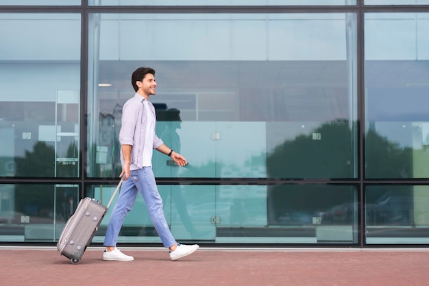 Férias e conceito de viagem Homem andando com mala de bagagem no aeroporto