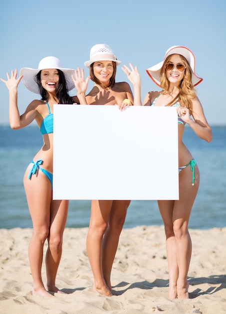 férias e férias de verão - garotas de biquíni segurando um quadro branco na praia