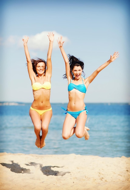 férias e férias de verão - garotas pulando na praia