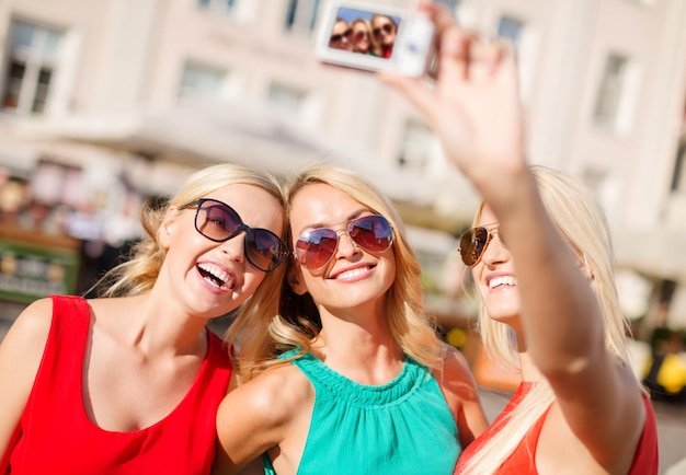 férias e turismo, conceito de tecnologia moderna - lindas garotas tirando foto com câmera digital na cidade