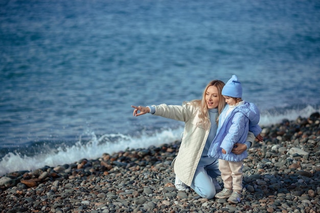 Férias em família no mar no outono ou na primavera Feliz família mãe e filha em uma caminhada à beira-mar