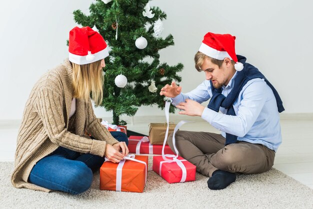 Férias, família e conceito festivo - casal com presentes de Natal em casa.