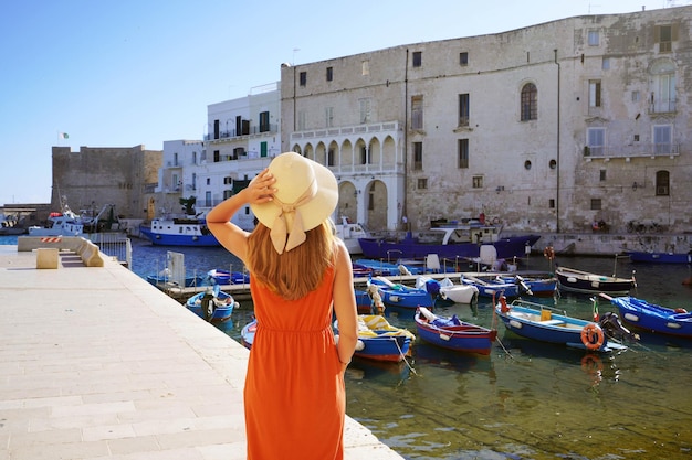 Férias na Apúlia Itália Vista traseira da bela garota fashion apreciando a vista do antigo porto de Monopoli na Apúlia Itália Férias de verão na Europa