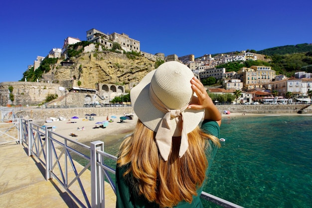 Férias na Calábria Vista traseira de uma bela mulher olhando a fortaleza e a vila de Pizzo na Calábria Férias de verão na Itália