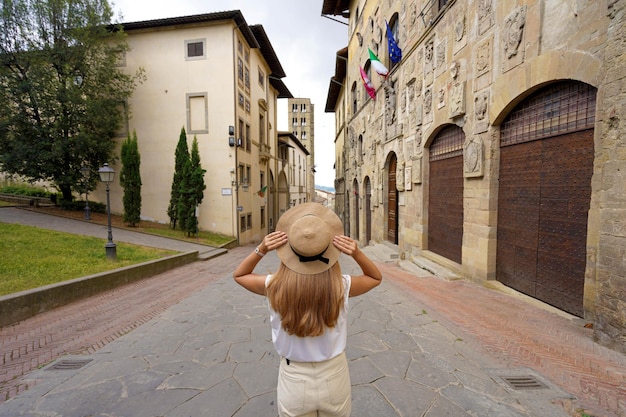 Férias na Itália Vista traseira da bela viajante segurando chapéu gosta de visitar a cidade histórica de Arezzo Toscana Itália