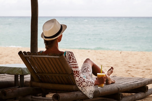 Férias na praia. slim mulher bonita em chapéu de sol deitado na espreguiçadeira