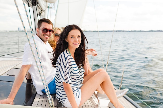 férias, viagens, mar, amizade e conceito de pessoas - amigos sorridentes sentados no convés do iate