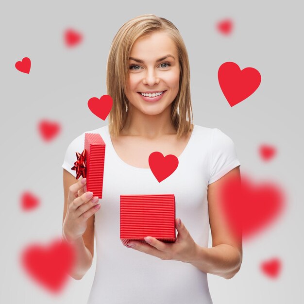 ferien, liebe, glück und valentinstagkonzept - schönes mädchen mit geschenkbox und fliegenden roten herzen