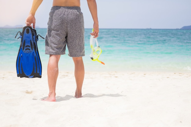 Ferien-Rückseite des Mannes Schnorchelausrüstung auf tropisch auf dem Strand halten