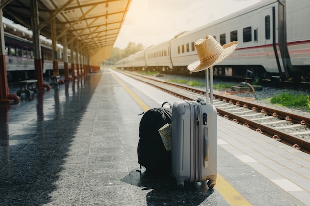 Ferien- und Reisekonzept. Reisetasche, Strohhut und Karte am Bahnhof