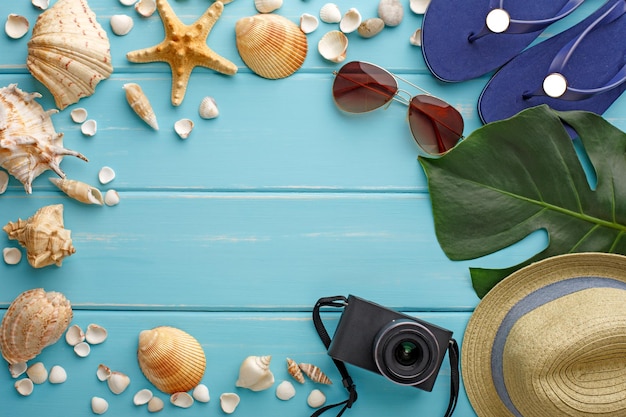 Ferienhintergrund auf blauem Holz, Draufsicht mit Kopienraum. Strandaccessoires, Flip-Flops und Muscheln