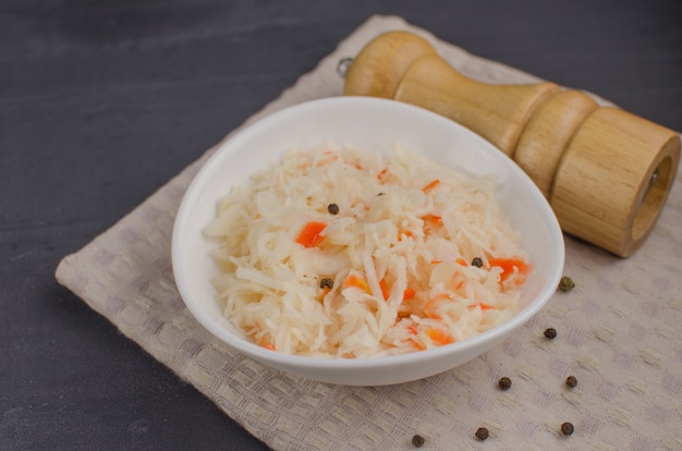 Fermentierter Kohl - Sauerkraut mit Kräutern und Gewürzen auf dem Holzhintergrund. Fermentiertes Essen. Speicherplatz kopieren.