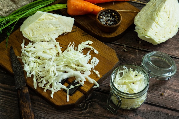Fermentiertes Essen Bereiten Sie hausgemachte Sauerkrautgläser mit Karotten auf rustikalem Holztisch zu