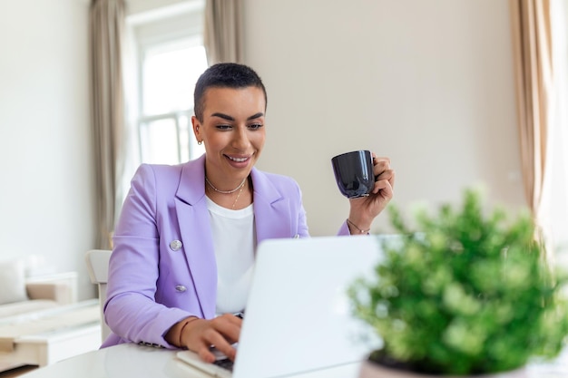 Fernarbeitstechnologie und Menschenkonzept glückliche lächelnde junge schwarze Geschäftsfrau mit Laptop-Computer und Papiere, die im Heimbüro arbeitet