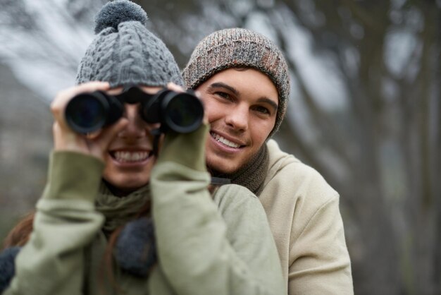 Ferngläser Natur und glückliches Paar in Waldreise und Abenteuer im Wandern Porträt für Kohlenstoff-Fußabdruck-Reisen Gesicht eines jungen Mannes und einer jungen Frau mit Outdoor-Ausrüstung für Vogelbeobachtung im Winter und im Wald