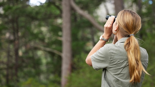 Foto fernglas wald und frau erkunden in der natur reisereise oder outdoor-abenteuer für die erforschung des co2-fußabdrucks beobachten sie die suche und unterstützen sie personen bei der vogelbeobachtung in dschungelwäldern oder in einer grünen öko-umgebung