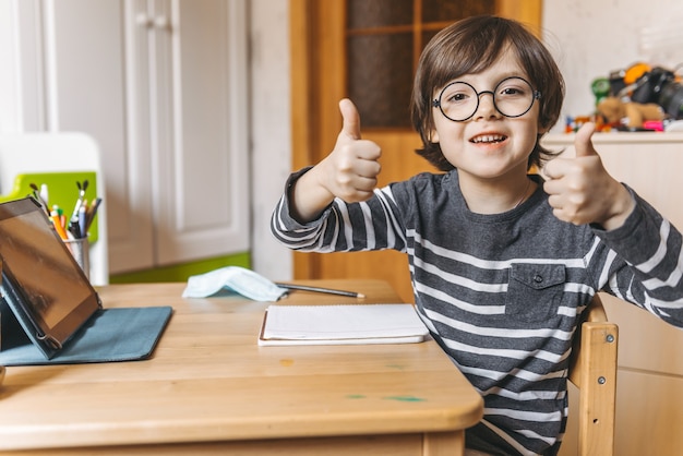 Fernunterricht für Kinder während der Coronavirus-Epidemie. Ein Junge sitzt an einem Tisch und erledigt Aufgaben eines Lehrers im Internet.