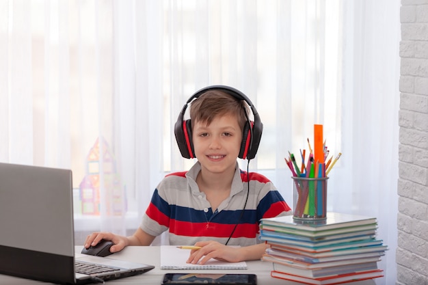 Fernunterricht Kind, das Hausaufgaben mit digitalem Tablett schreibt. Konzept Online-Bildung.