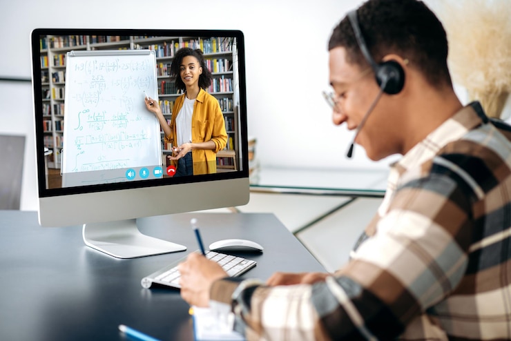 Foto fernunterrichts-webinar online-vortrag hispanic kluger männlicher student sitzt am schreibtisch, benutzt den computer, hört sich einen online- vortrag an und macht sich notizen, weibliche afroamerikanische lehrerin auf dem bildschirm