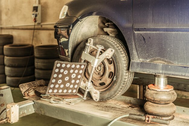 Ferramenta anexada à roda de um carro levantada com um macaco para alinhar a direção em uma garagem