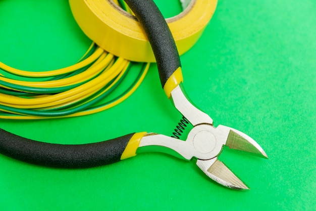 Ferramenta de alicate e fios para eletricista close-up em espaço verde