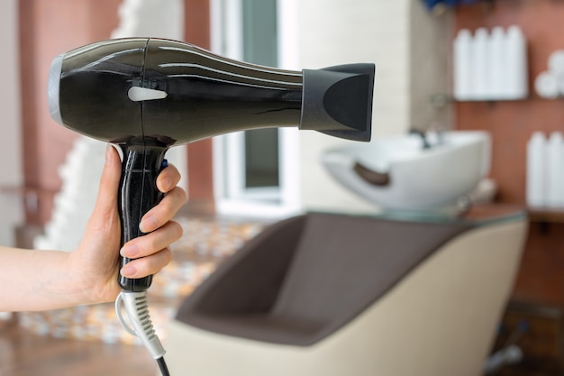 Mão feminina segurando secador de cabelo profissional isolado no fundo  branco. equipamento de salão, recorte