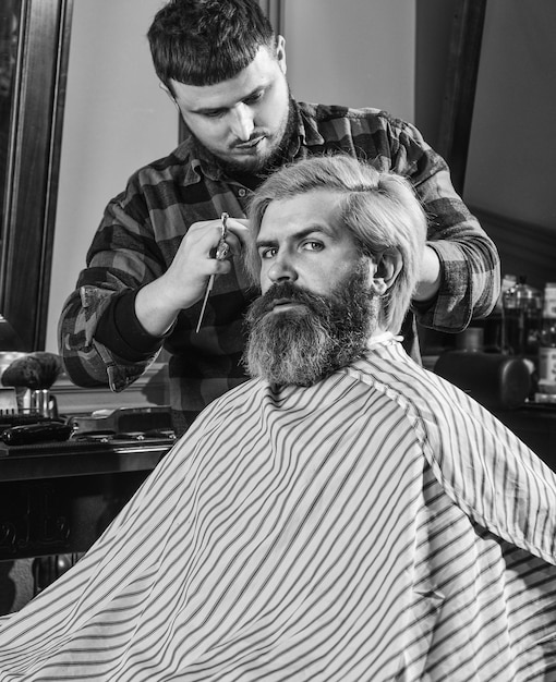 Ferramentas de barbeiro masculino bonito na barbearia cabeleireiro bonito cortando o cabelo do cliente masculino cabeleireiro atendendo o cliente na barbearia estilista pessoal barbeiro retrô e vintage projetando corte de cabelo