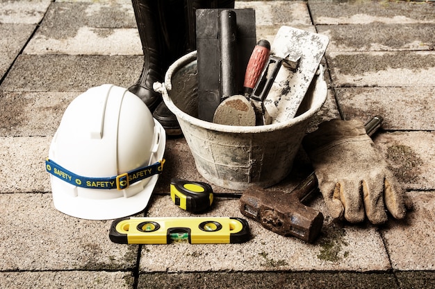 Ferramentas de construção ou equipamentos de segurança com capacete branco no chão de tijolo