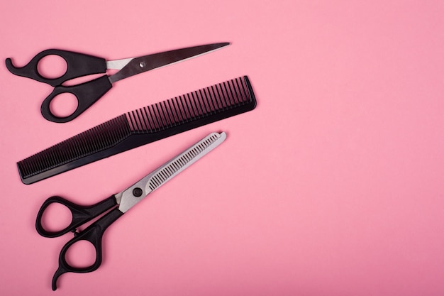 Ferramentas de corte de cabelo em um fundo rosa, copie o espaço