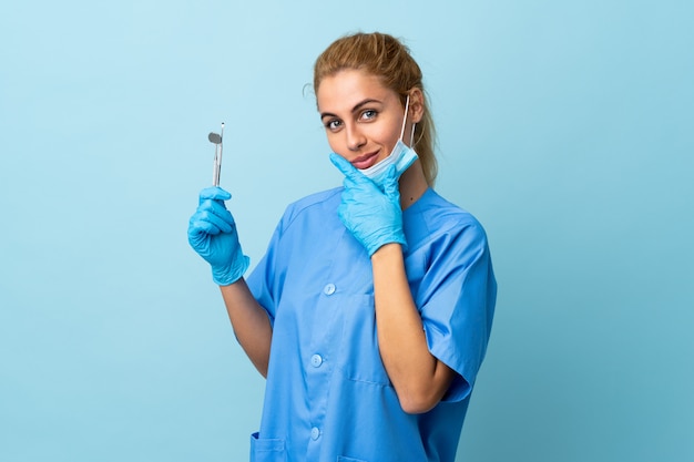 Ferramentas de exploração do dentista da jovem mulher sobre o azul isolado que pensa uma ideia