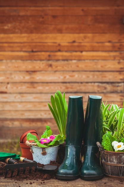 Ferramentas de jardinagem e flores com botas de borracha e espaço de cópia na parede do celeiro