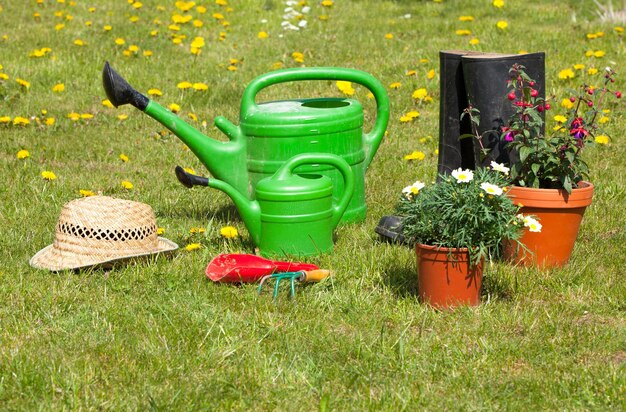 Ferramentas de jardinagem e um chapéu de palha na grama do jardim