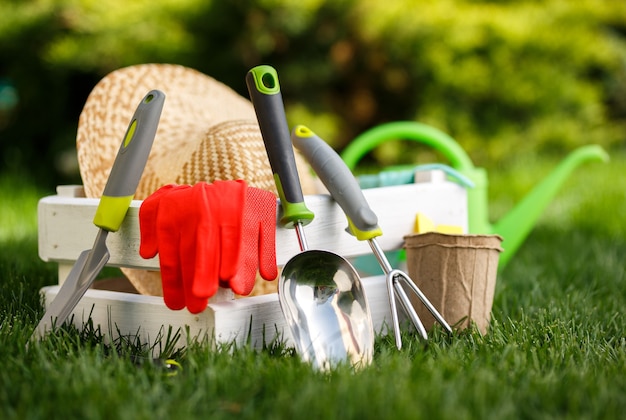 Foto ferramentas de jardinagem e um chapéu de palha na grama do jardim.